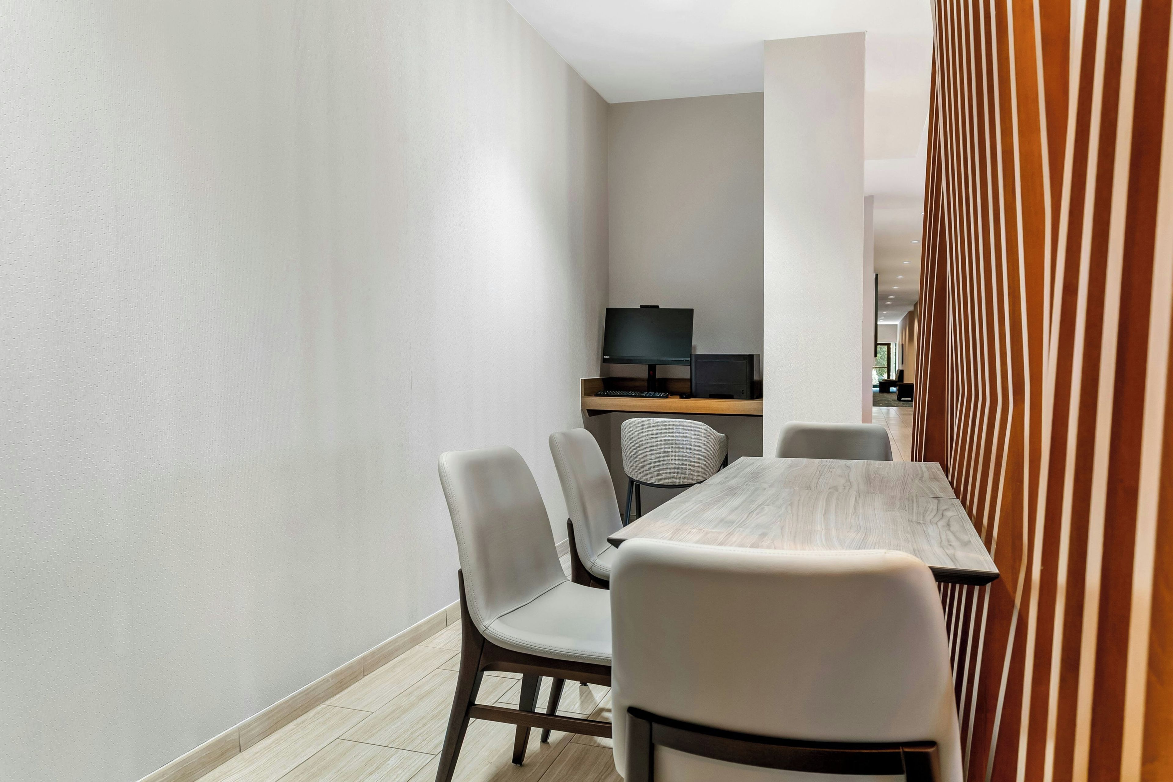 Ein moderner Essbereich mit Holztisch und vier Stühlen, einem Fernseher auf einem Schrank und einer gestreiften Raumtrennung.