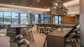 A modern restaurant with a bar area, high tables, and stools. - SpringHill Suites by Marriott Gainesville Haymarket (Gainesville)