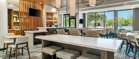 A modern bar area with a long counter, seating, and a television.