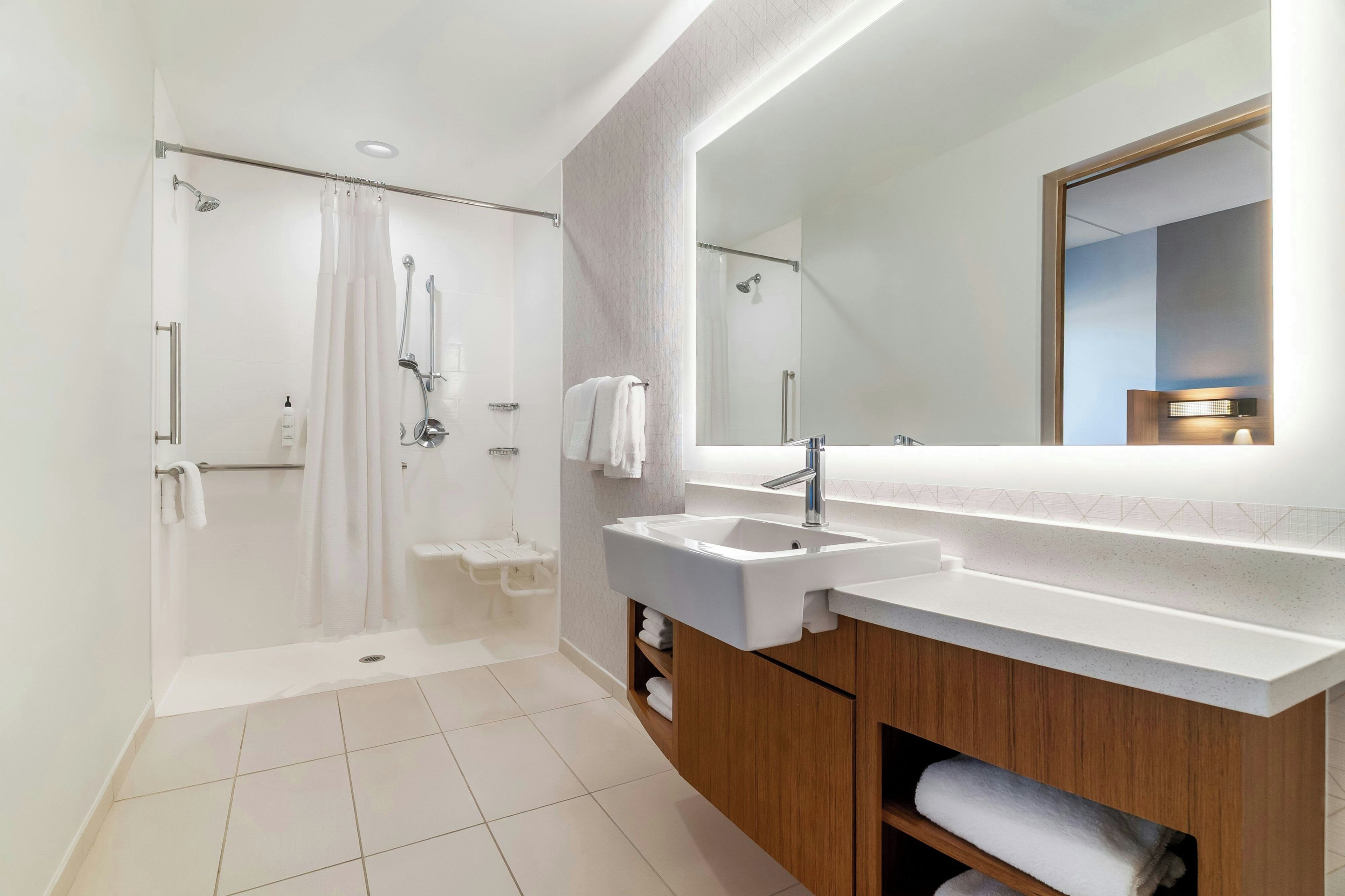 A modern bathroom with a walk-in shower, a large mirror, and a dual sink vanity.