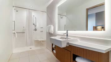 A modern bathroom with a walk-in shower, a large mirror, and a dual sink vanity.