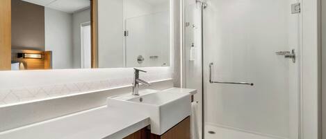 Une salle de bain moderne avec un grand miroir, un lavabo et une douche à parois de verre.