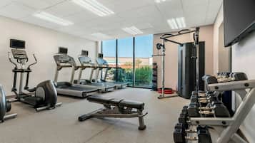 Un gimnasio con cintas de correr, elípticas, prensa de banca y mancuernas.