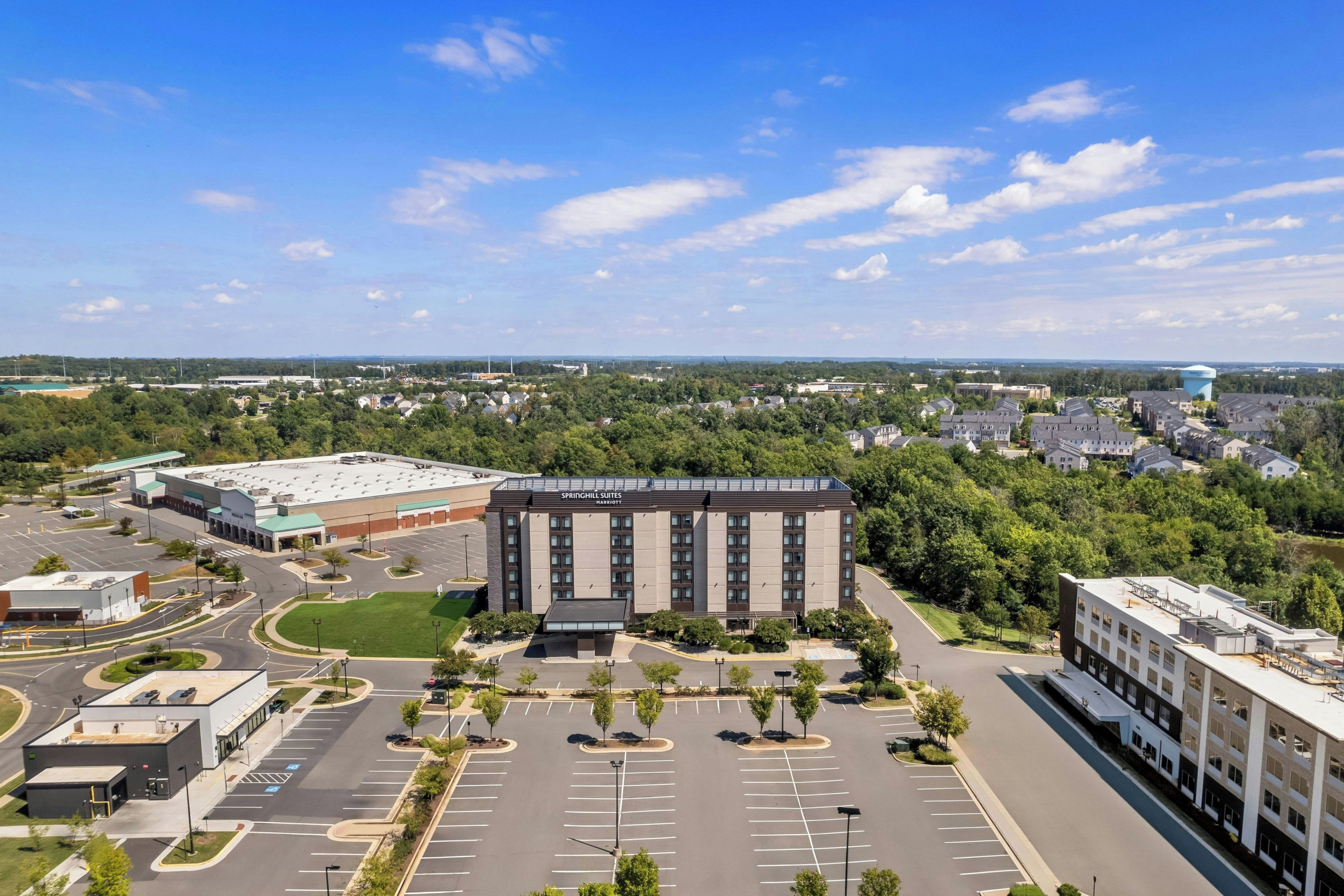 A large hotel with a parking lot and surrounding greenery.