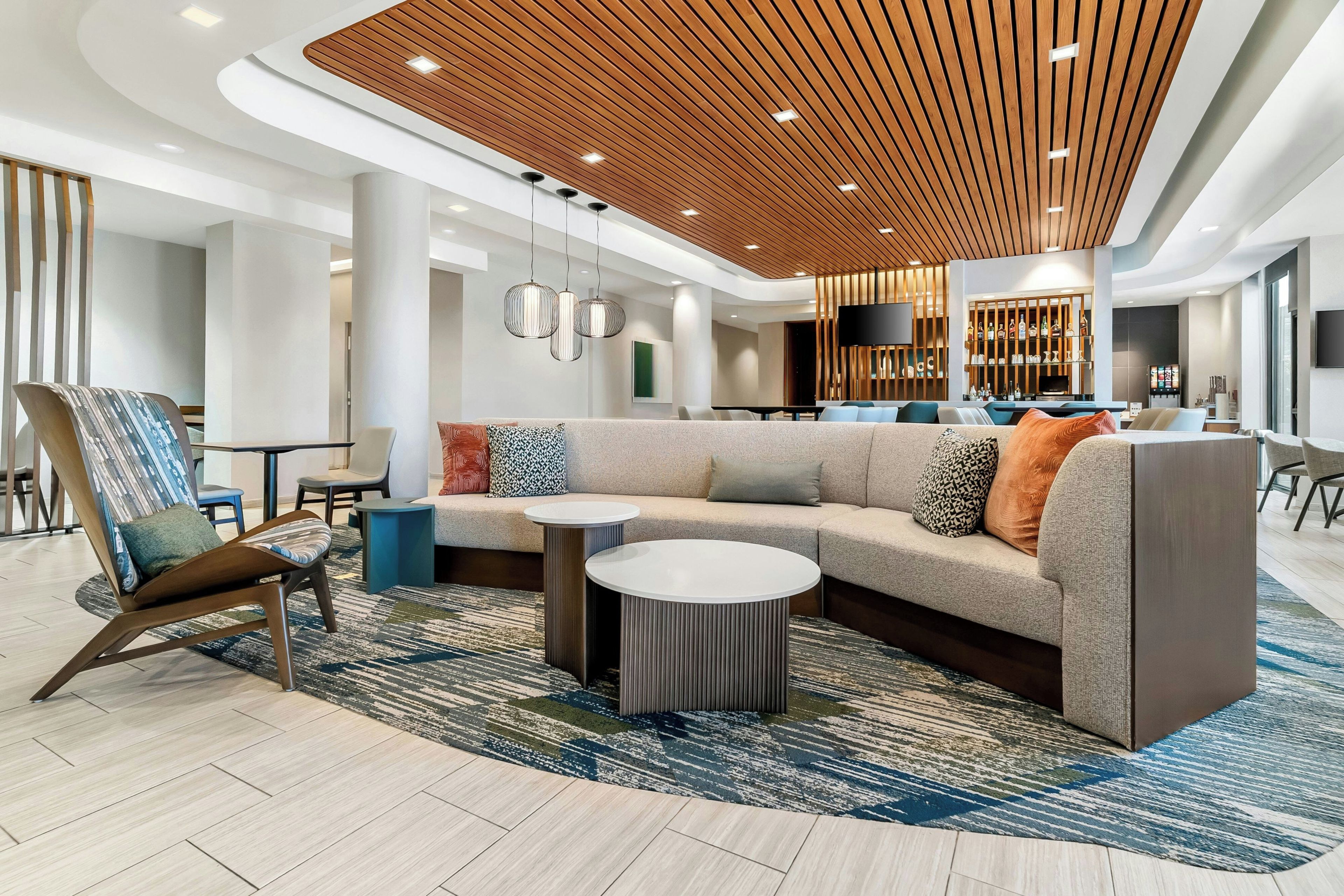 A modern lobby with a sectional sofa, a round coffee table, and a patterned rug.
