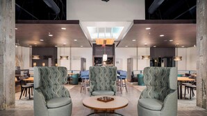A modern lobby with high ceilings, exposed ductwork, and a central round table with chairs. - Courtyard by Marriott Niagara Falls USA (Niagara Falls)