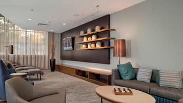 A modern living room with a sofa, armchairs, a coffee table, and a TV wall unit.