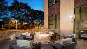 An outdoor seating area with wicker furniture and a stone fire pit. - Courtyard by Marriott Niagara Falls USA (Niagara Falls)