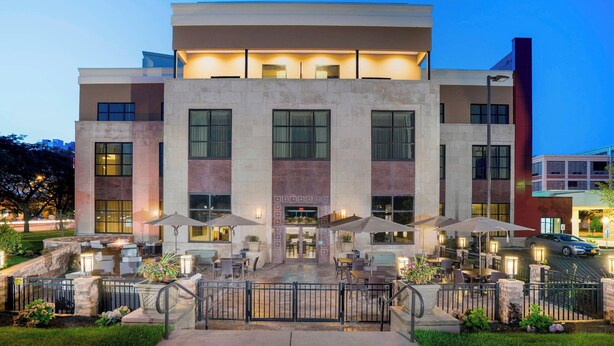 A modern hotel with a central entrance, outdoor seating area with umbrellas, and a well-lit facade. - Courtyard by Marriott Niagara Falls USA (Niagara Falls)
