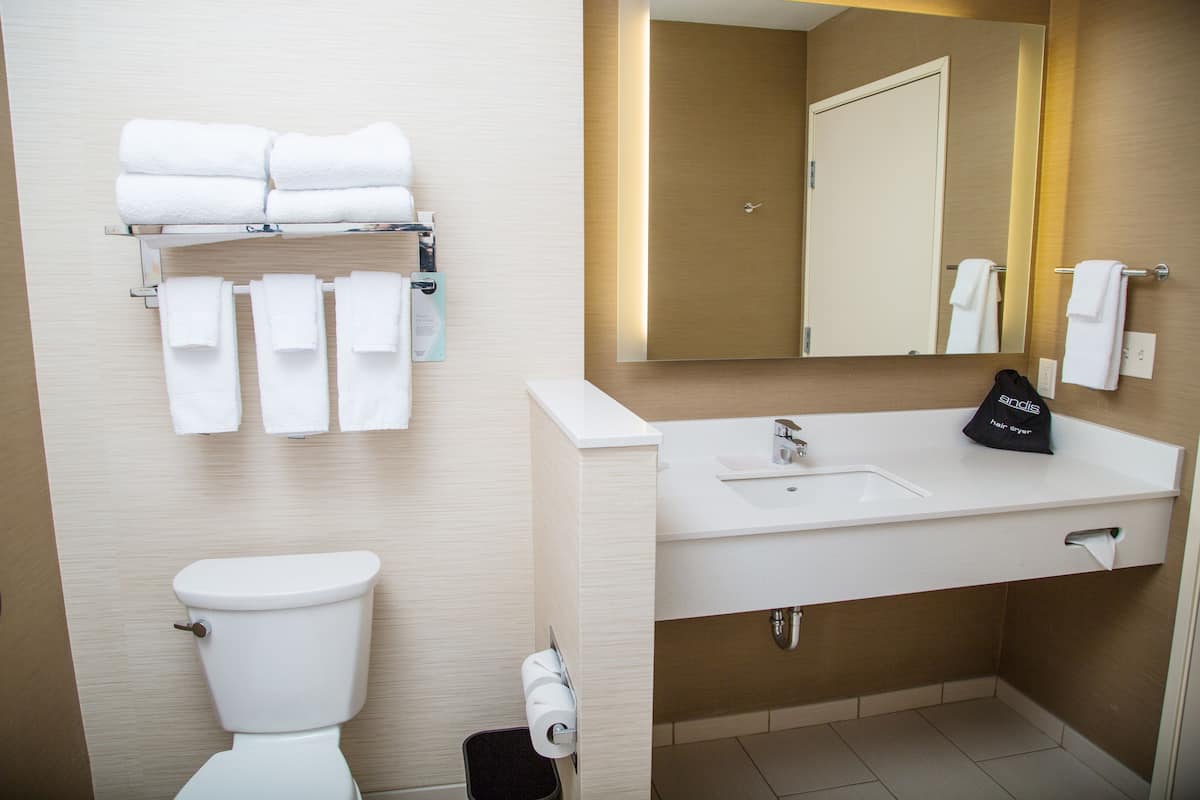 Un baño moderno con inodoro, lavamanos y perchero para toallas.