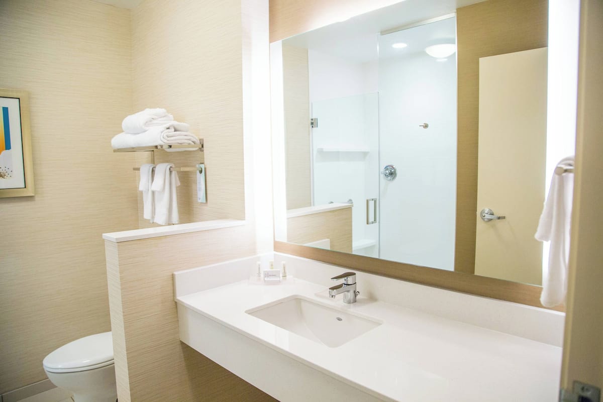 Un baño moderno con lavamanos, espejo y toallero blancos.