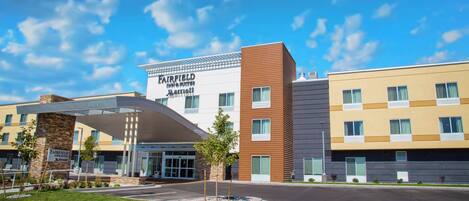 A Fairfield Inn & Suites by Marriott hotel with a modern design, featuring a prominent entrance and a landscaped area in front.