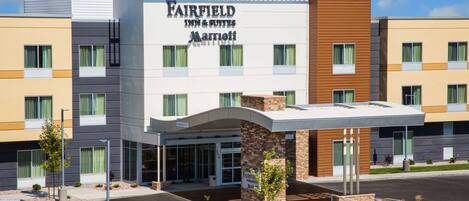 A Fairfield Inn & Suites Marriott hotel with a modern design, featuring a prominent entrance, a parking lot, and landscaped areas.