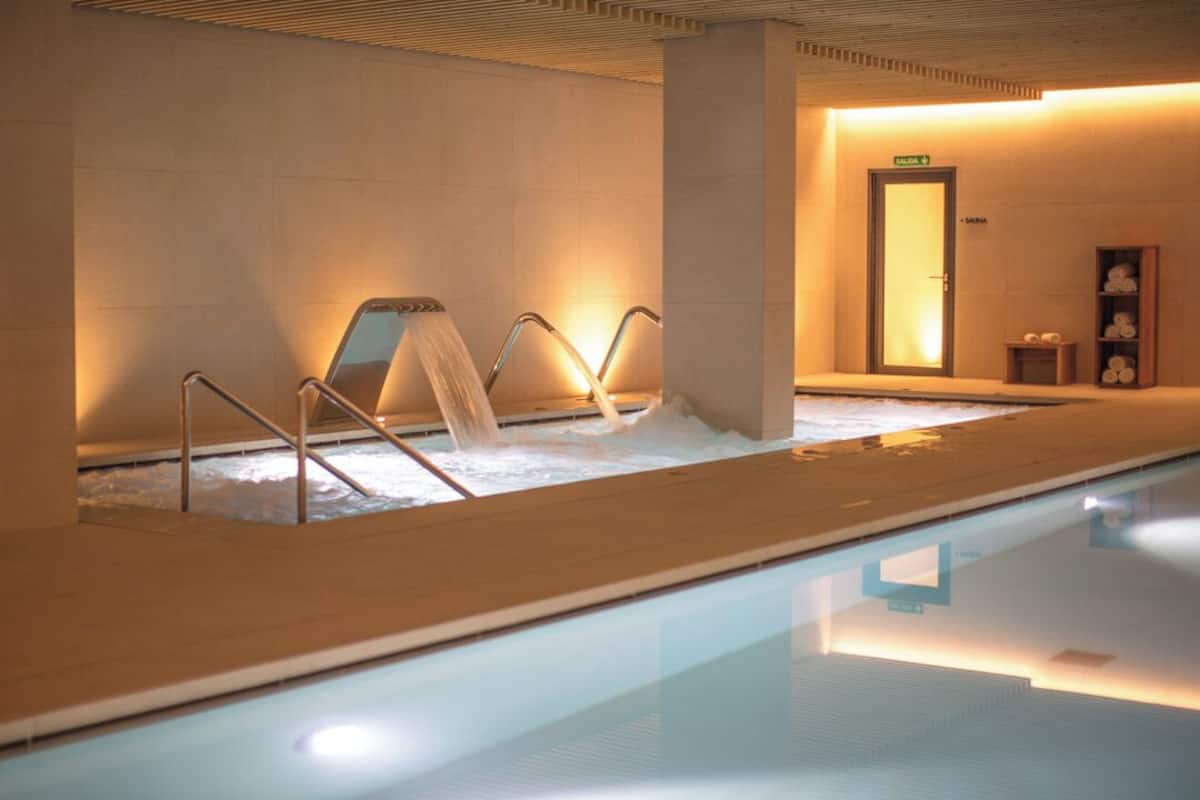 A spa area with a hot tub, a sauna, and a glass-enclosed pool.