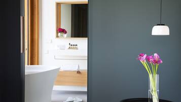 A modern bathroom with a freestanding bathtub, a mirror, and a vanity with toiletries.
