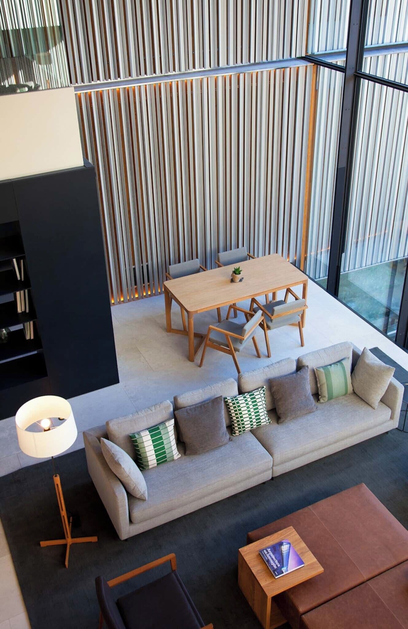 A modern living room with a sectional sofa, a wooden dining table, and a black bookshelf.