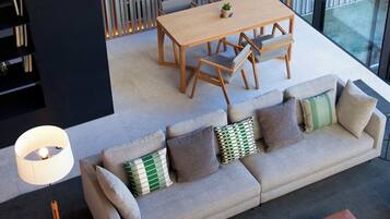 A modern living room with a sectional sofa, a wooden dining table, and a black bookshelf.