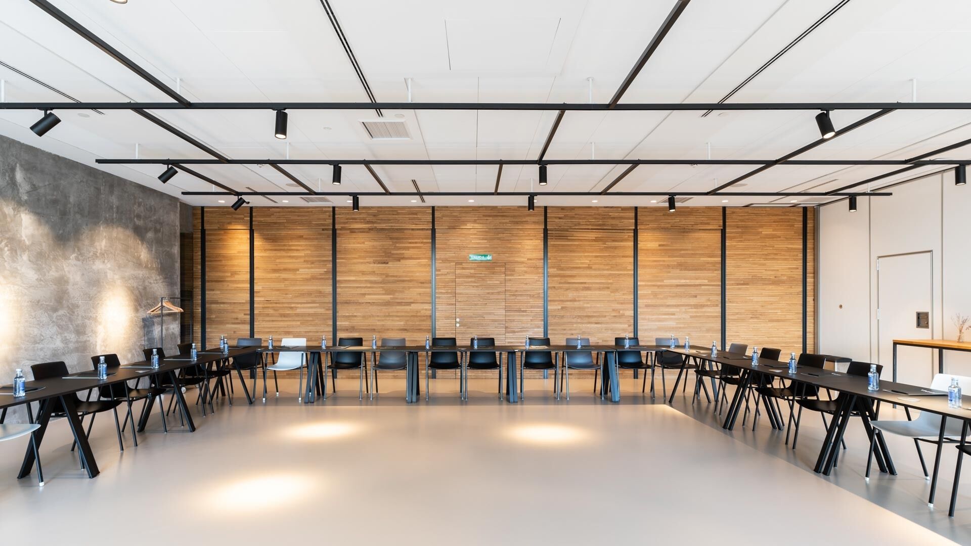 Un salón de conferencias con una larga mesa, varias sillas y un revestimiento de madera en la pared.