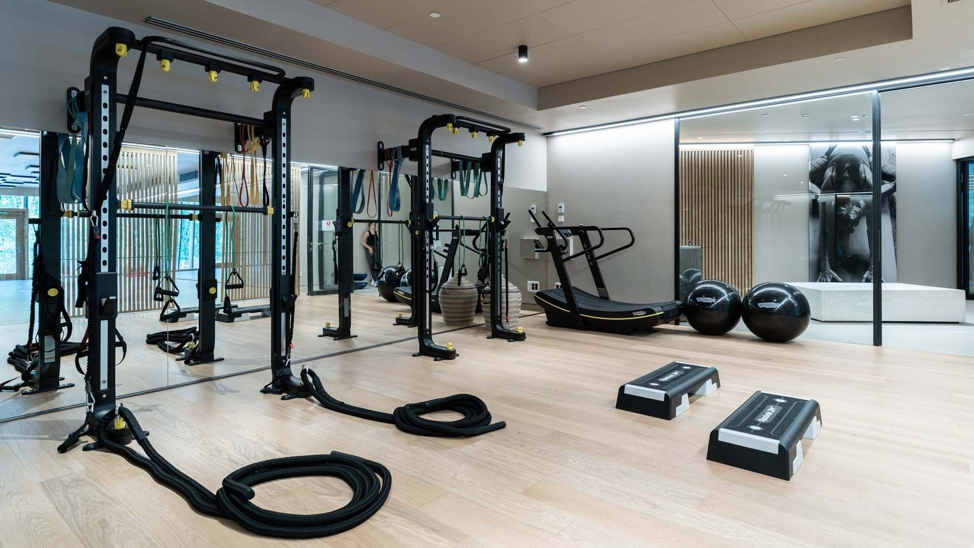 A modern gym with various exercise equipment, including weight machines, a treadmill, and free weights.