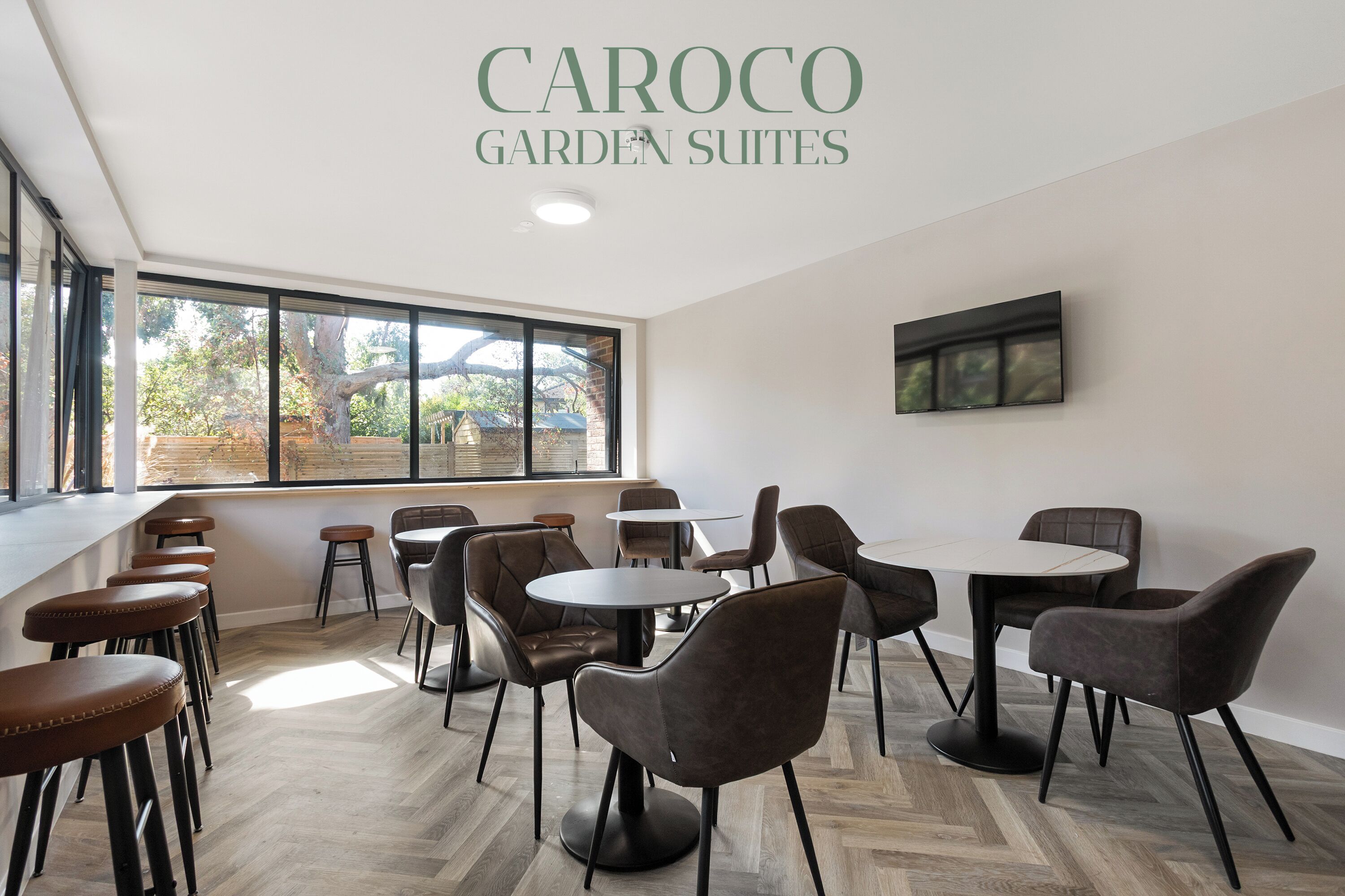 A modern interior with a bar area, multiple seating arrangements, and large windows providing natural light.
