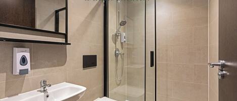 A modern bathroom with a glass-enclosed shower, a white sink, and a toilet.