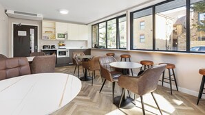 A modern interior with a dining area, kitchen, and large windows. - Westciti Caroco Aparthotel (Croydon)