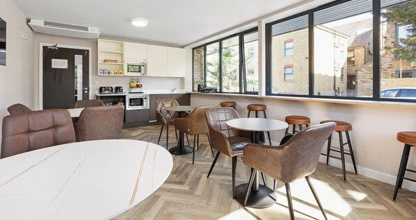 A modern interior with a dining area, kitchen, and large windows. - Westciti Caroco Aparthotel (Croydon)