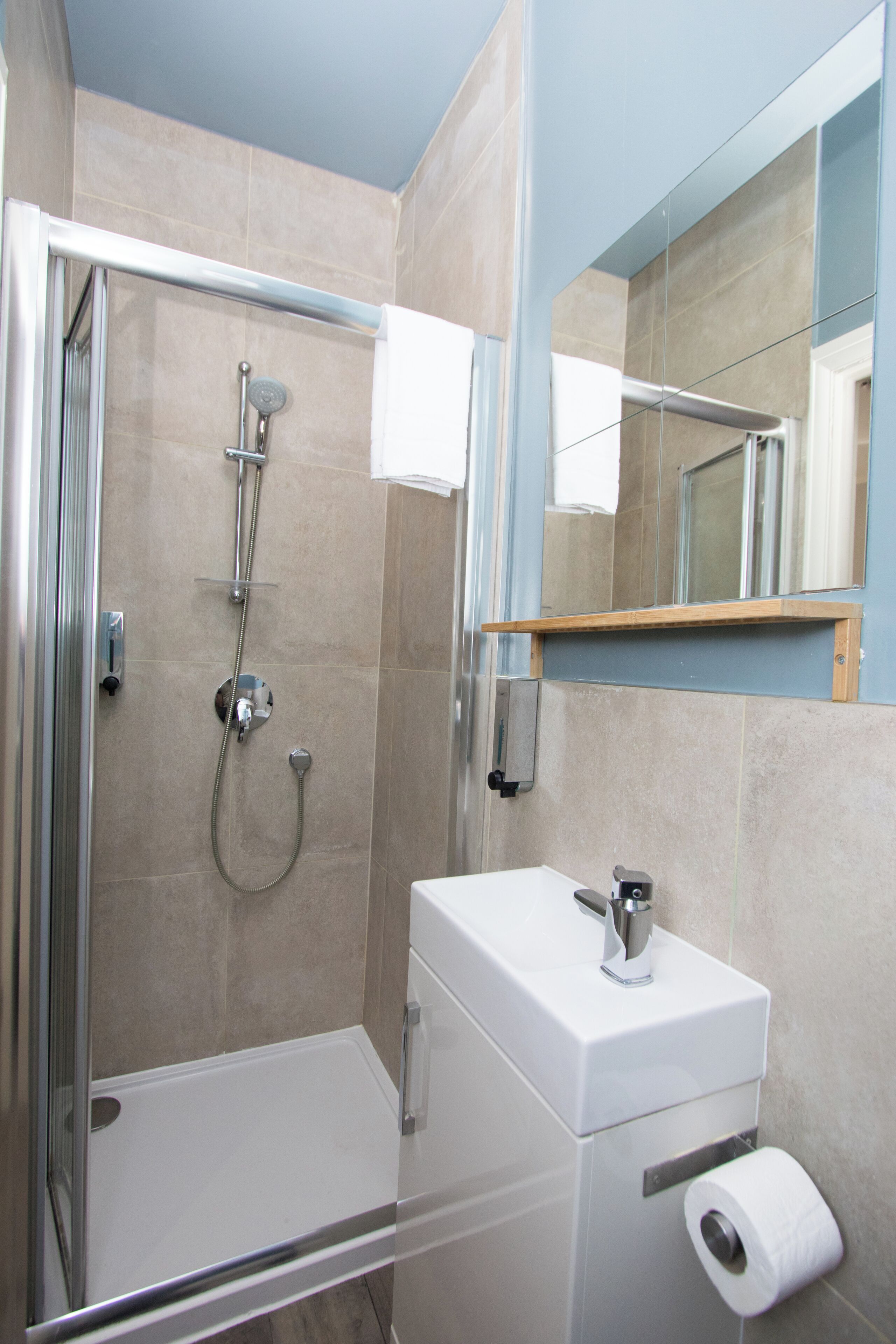 Une salle de bain moderne avec une douche à parois de verre, un lavabo blanc et un miroir.