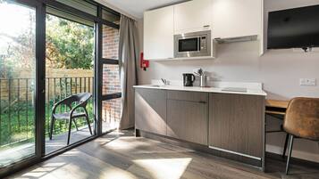 A modern kitchen with a built-in microwave, a flat-screen TV, and a sliding glass door leading to a balcony.