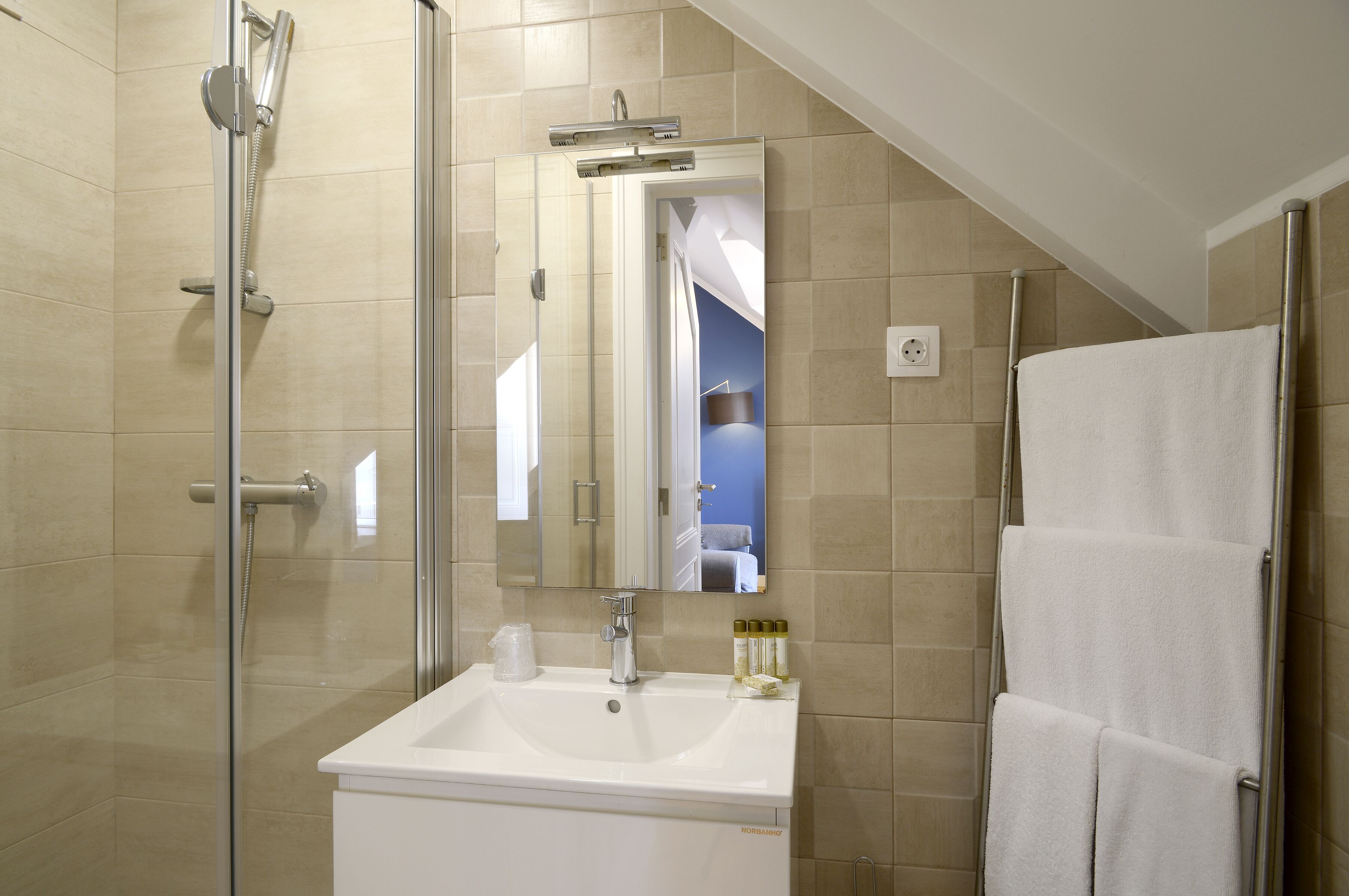 A modern bathroom with a glass-enclosed shower, a white sink, and a towel rack.