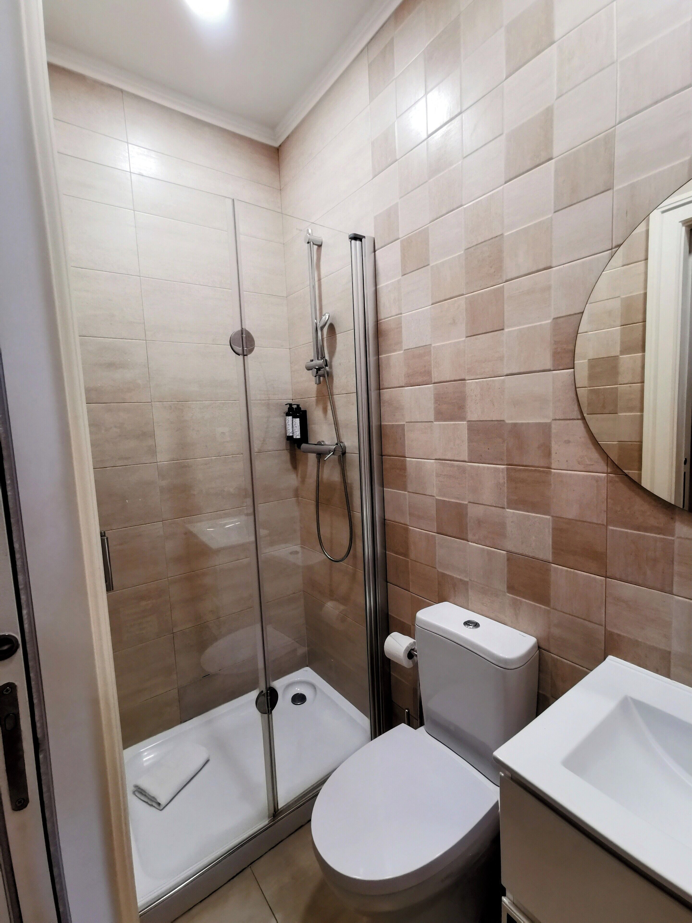 A modern bathroom with a glass-enclosed shower, a toilet, and a sink.
