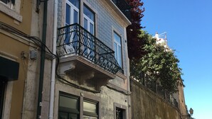 Un edificio con fachada de baldosas, un balcón con barandilla de hierro forjado y una pared cubierta de grafitis.