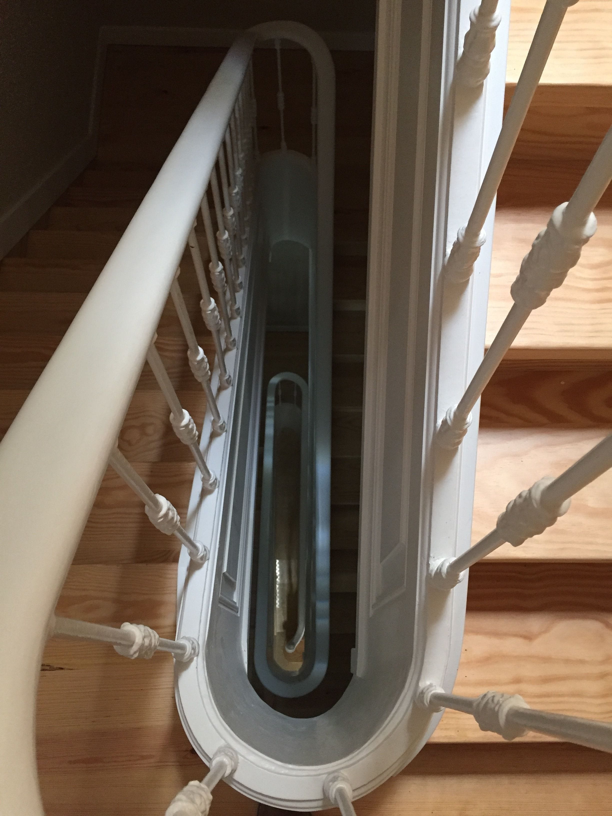 A white metal spiral staircase with a central handrail and steps.