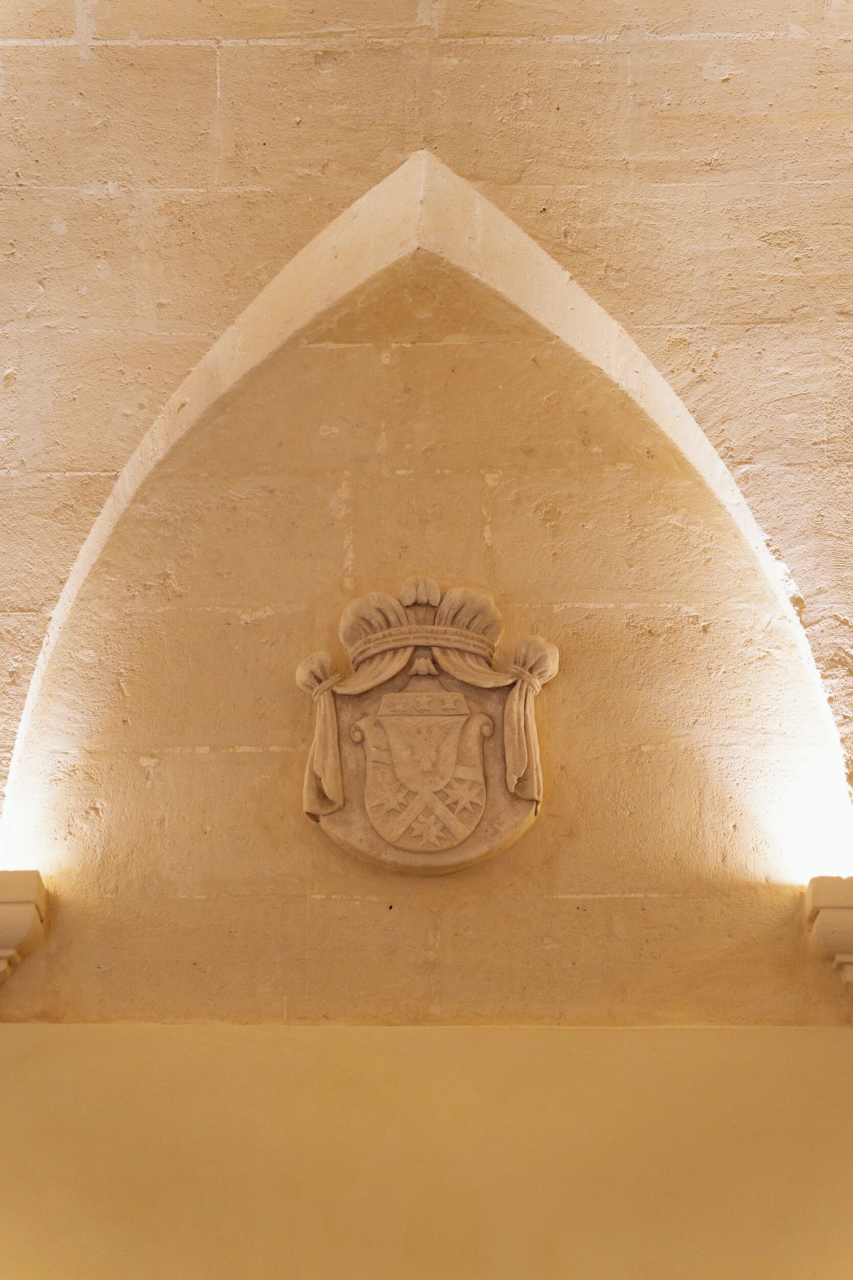 Une arche en pierre ornée d’un blason.