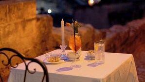 Una tavola imbandita per due, con candele, un bicchiere di succo d'arancia e una ciotola di frutta.