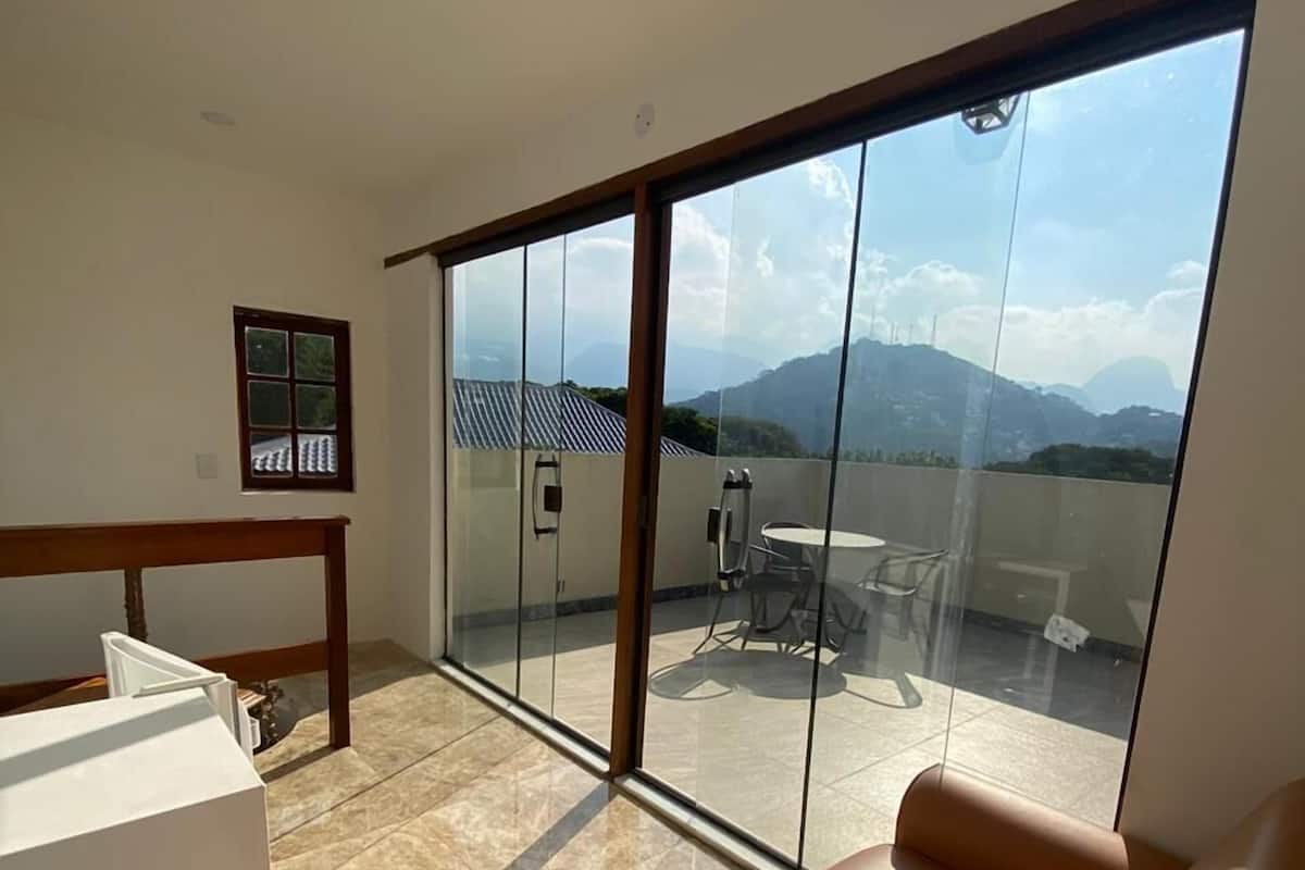 A modern room with a large sliding glass door leading to a balcony with a view of mountains.