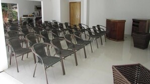 Una habitación con hileras de sillas de mimbre, un armario de madera y una puerta.