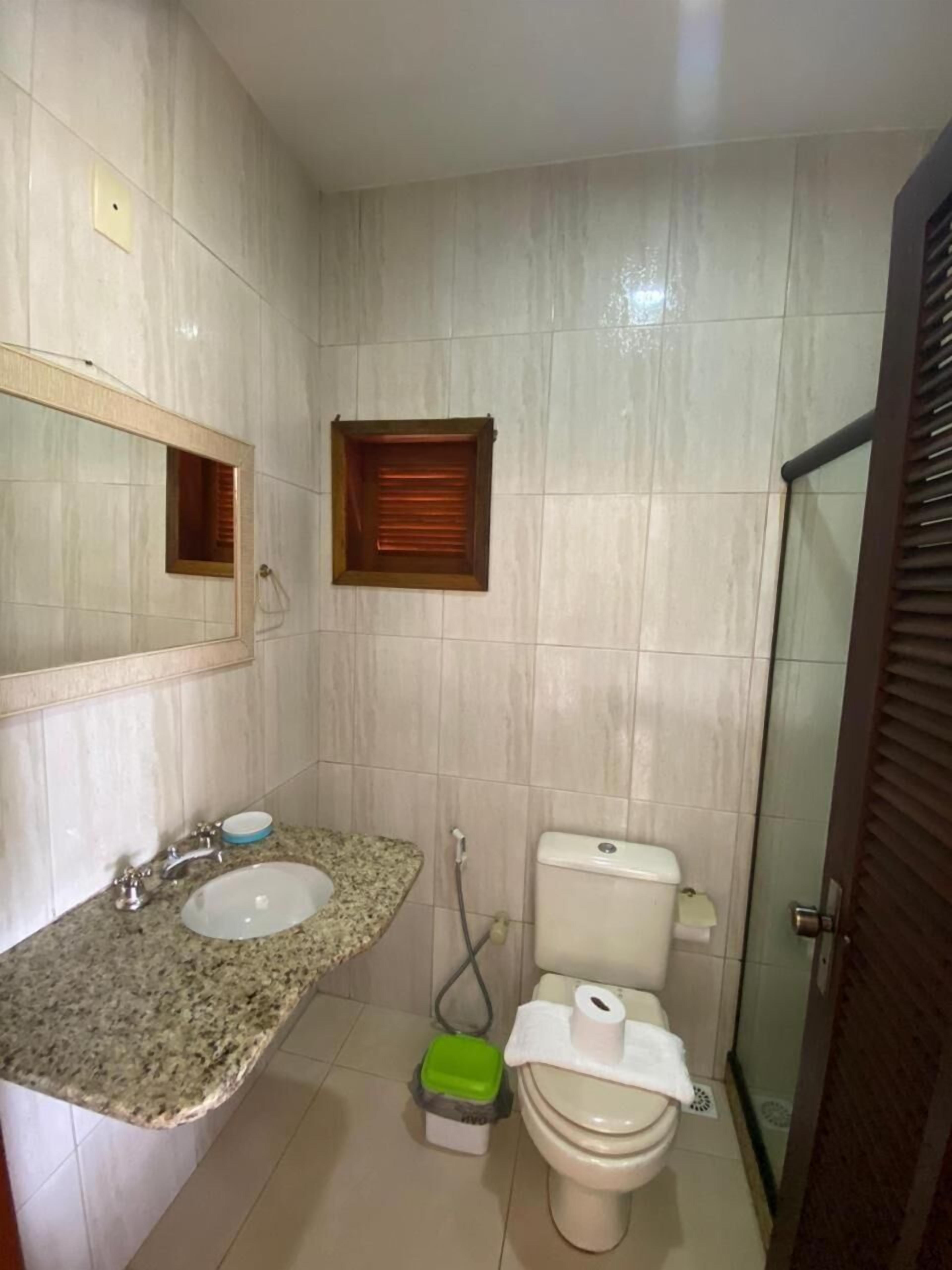 Une salle de bain avec un lavabo sur un plan de travail en granit, des toilettes et un espace douche.