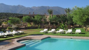 A pool area with lounge chairs and a stone wall. - La Bergerie (Ouirgane)