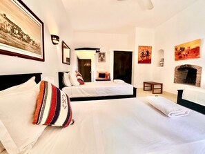 Quarto de hotel com duas camas, lareira e obras de arte nas paredes.
