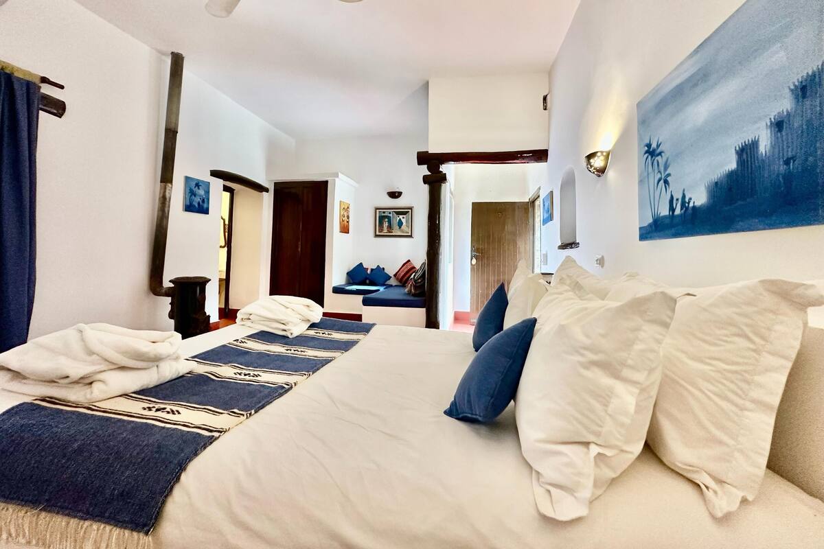 Une chambre d’hôtel avec un grand lit, un ventilateur de plafond et un tableau au mur.