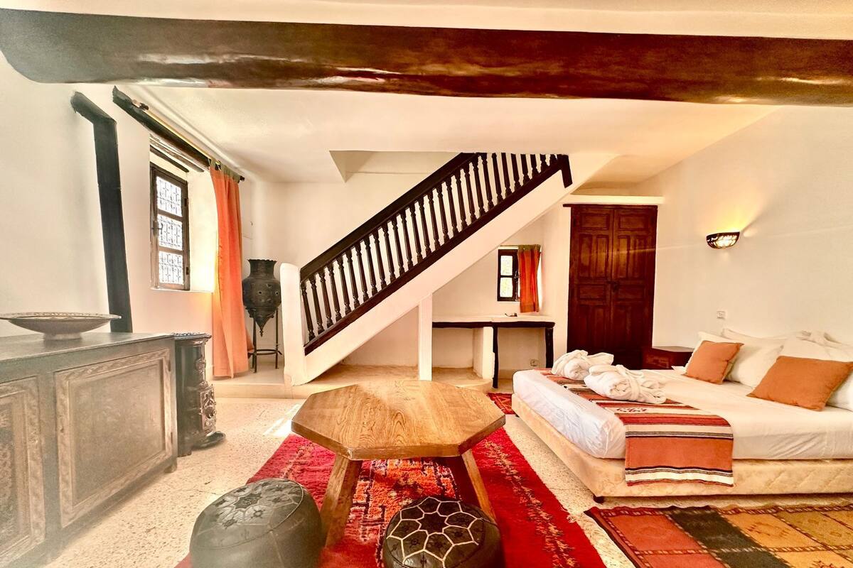 Un salon spacieux avec un escalier, un ensemble de canapés et une table basse.
