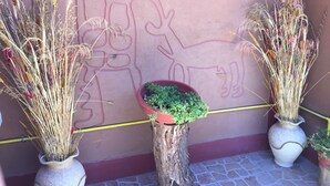 Two potted plants with dried grasses and a small green plant in a wooden stump. - Hostal Vilama (San Pedro de Atacama)