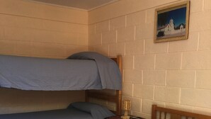 A room with two bunk beds, a small bedside table with a lamp, and a framed picture on the wall. - Hostal Vilama (San Pedro de Atacama)