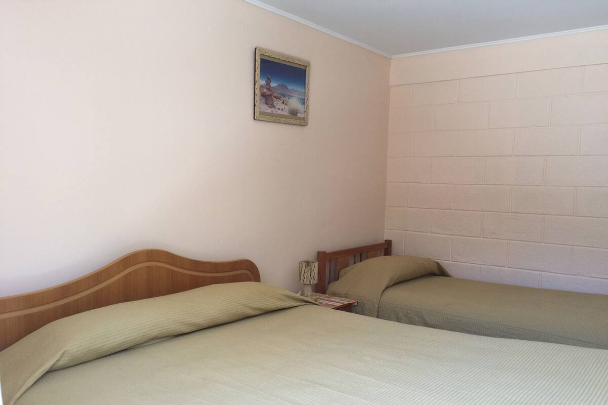 A room with two beds, a small table, and a picture on the wall.