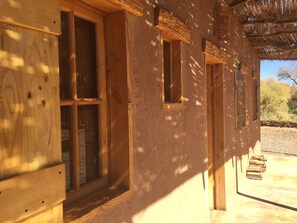 A wooden structure with multiple windows and a thatched roof. - Casas Valle de la Luna (San Pedro de Atacama)