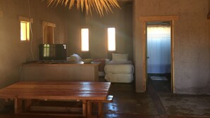 Una habitación rústica con una mesa de madera, un televisor y una cama.