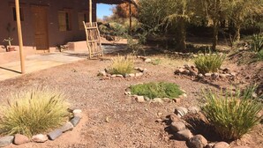 Un edificio rústico con techo de paja, rodeado de un jardín de grava con diversas plantas y rocas.