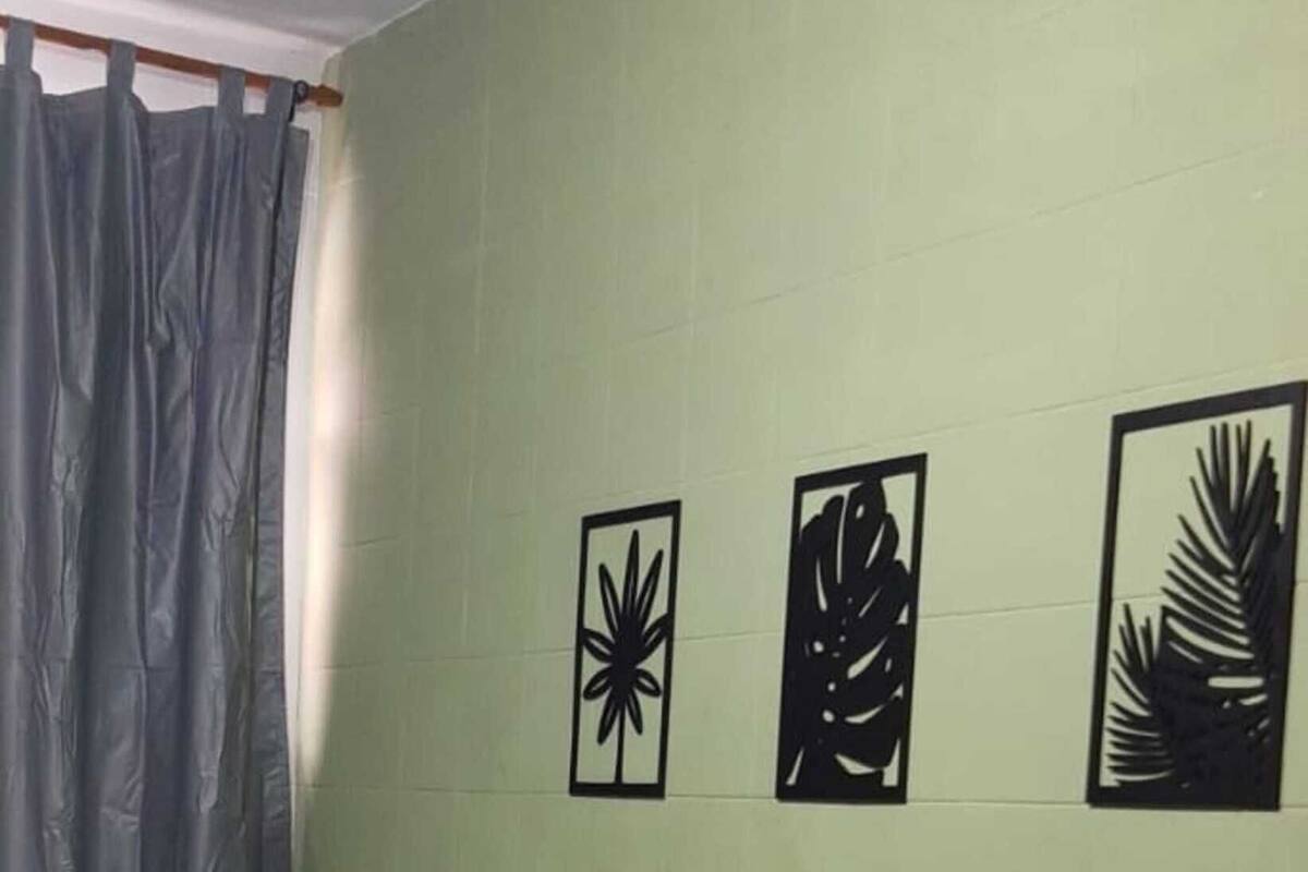A room with a bed, a green wall, and three black wall art pieces.