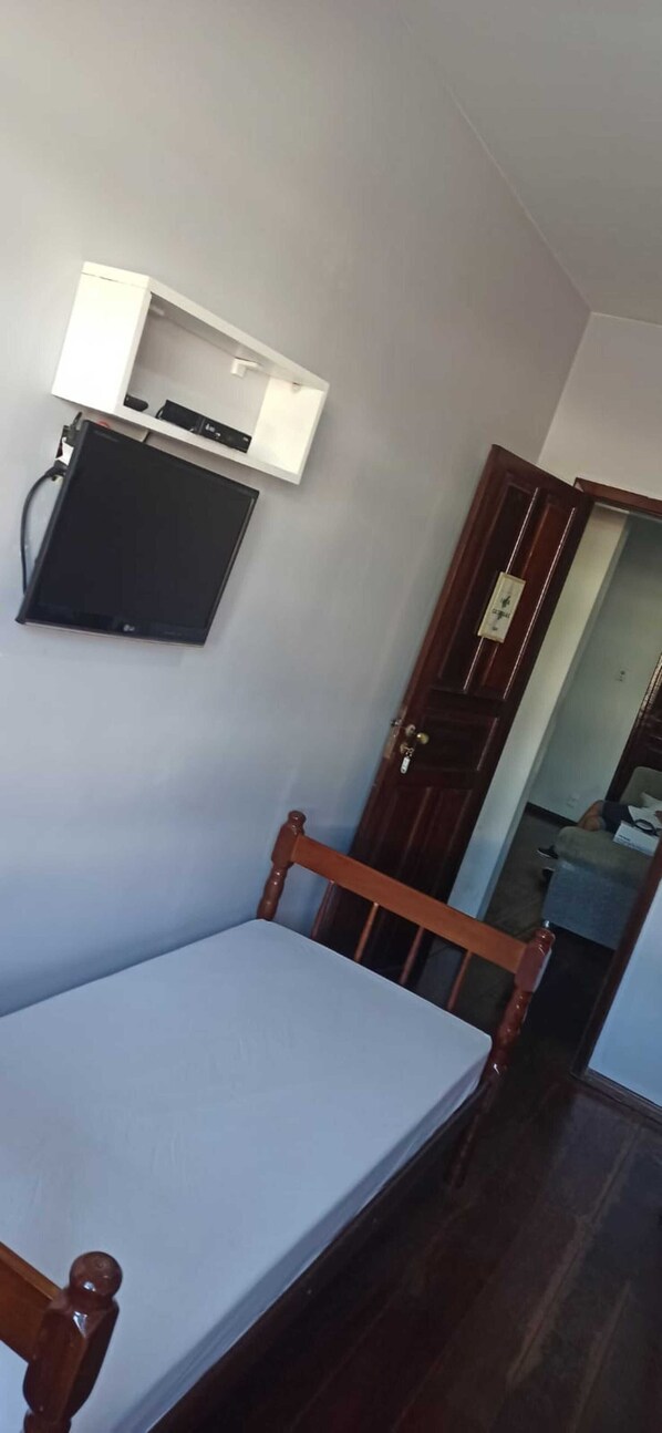 A room with a bed, a desk with a computer, and a wardrobe.